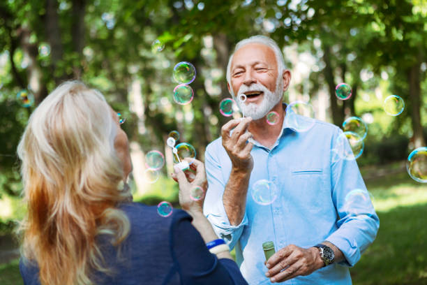 two senior outside blowing bubbles and laughing